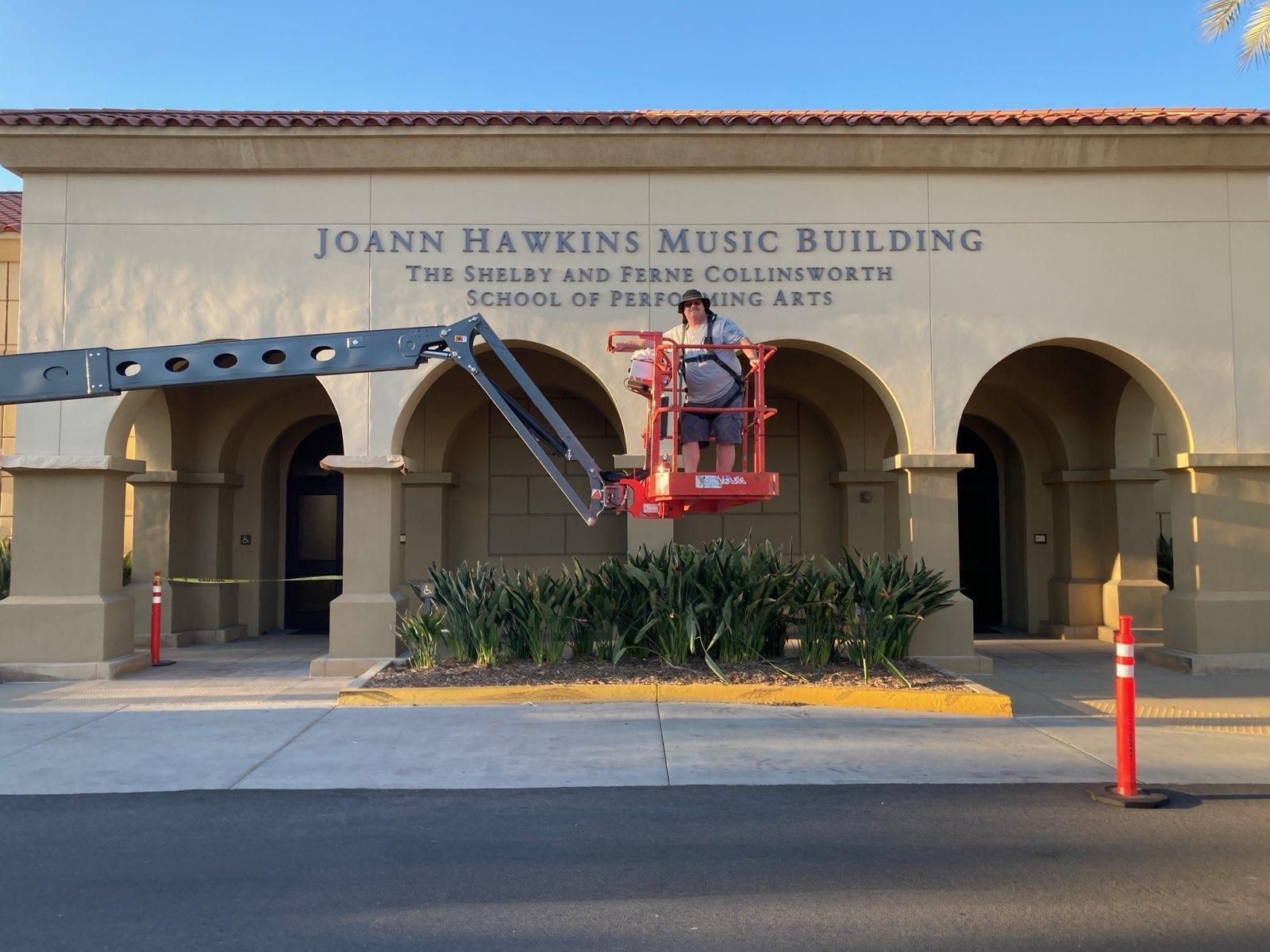 Johns Hawkins Music Building entrance with arches, blue sky, and a red lift basket near the doorway