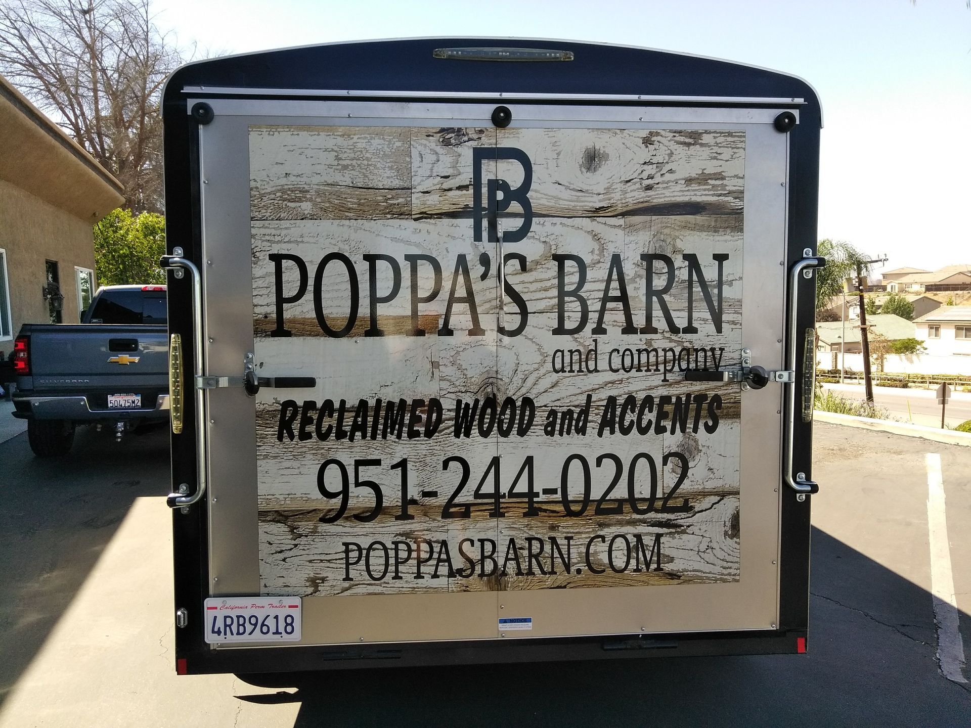 Trailer with “Pappa’s Barn” sign advertising reclaimed wood and accents, phone number, and website.