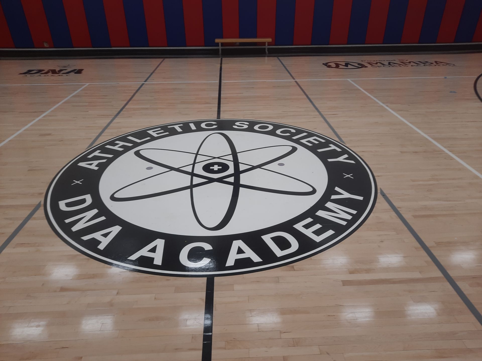 Gymnasium floor with a large NASA logo and “DNA Academy” painted at center court.