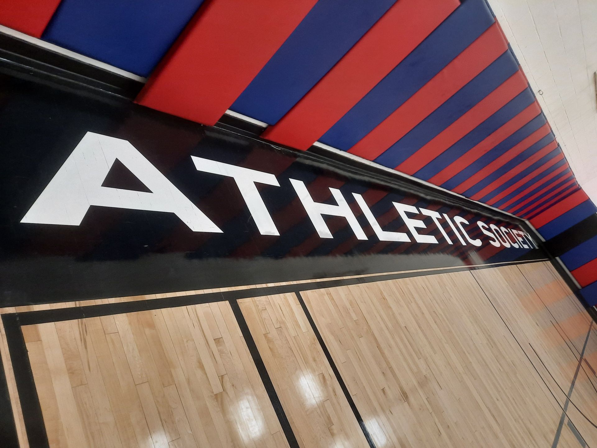 Athletics sign on a red-and-blue gym wall above wooden lockers