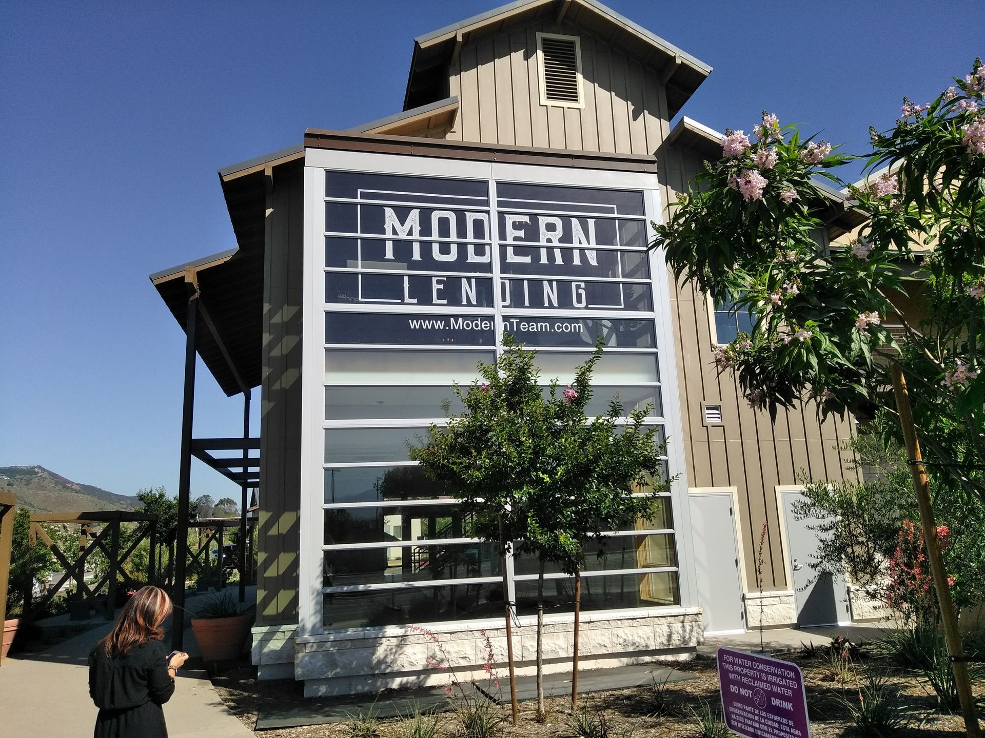 Modern Lending building with large sign, framed by trees and blue sky