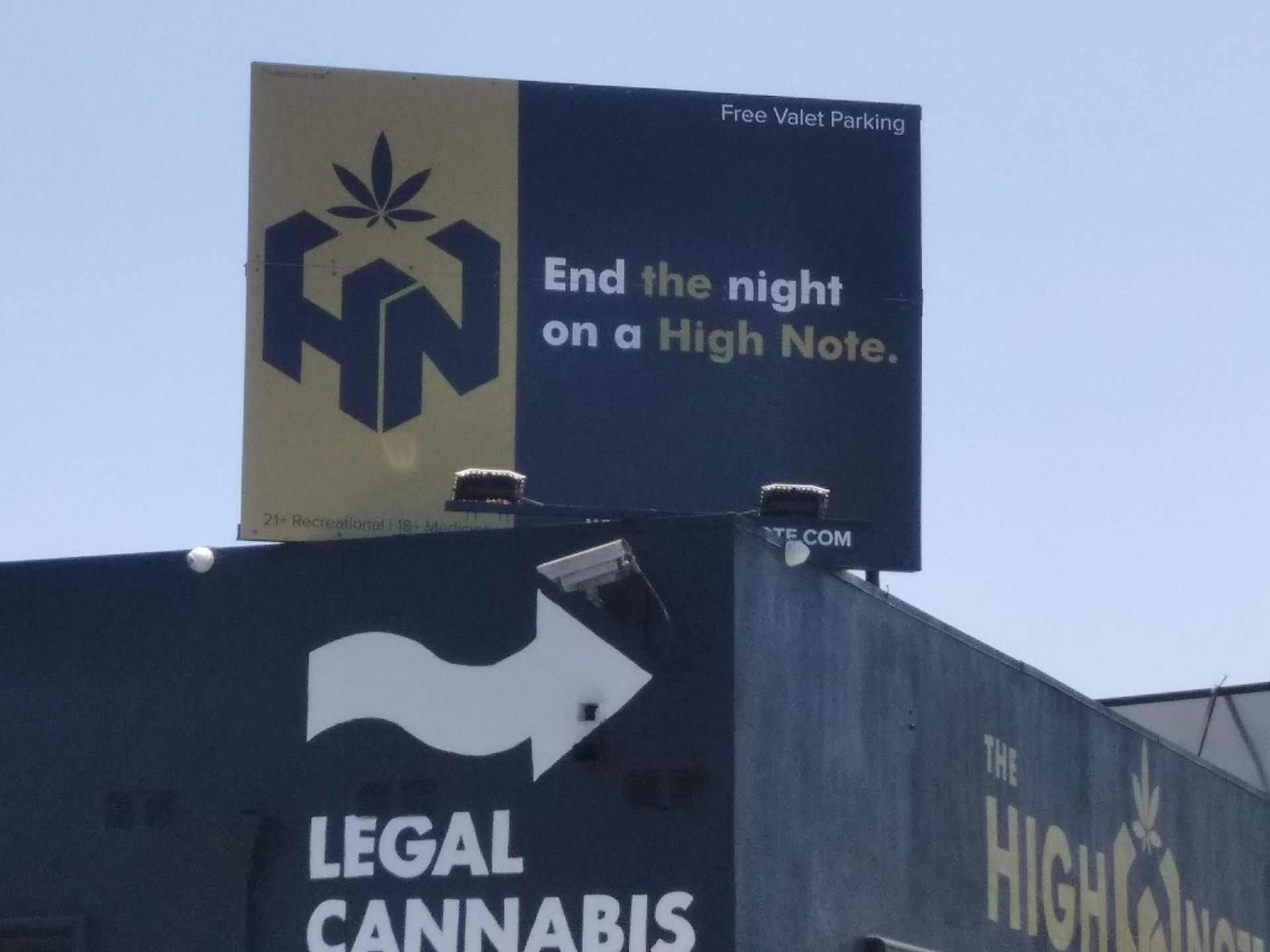 Billboard above a legal cannabis store reads “End the night on a High Note.”