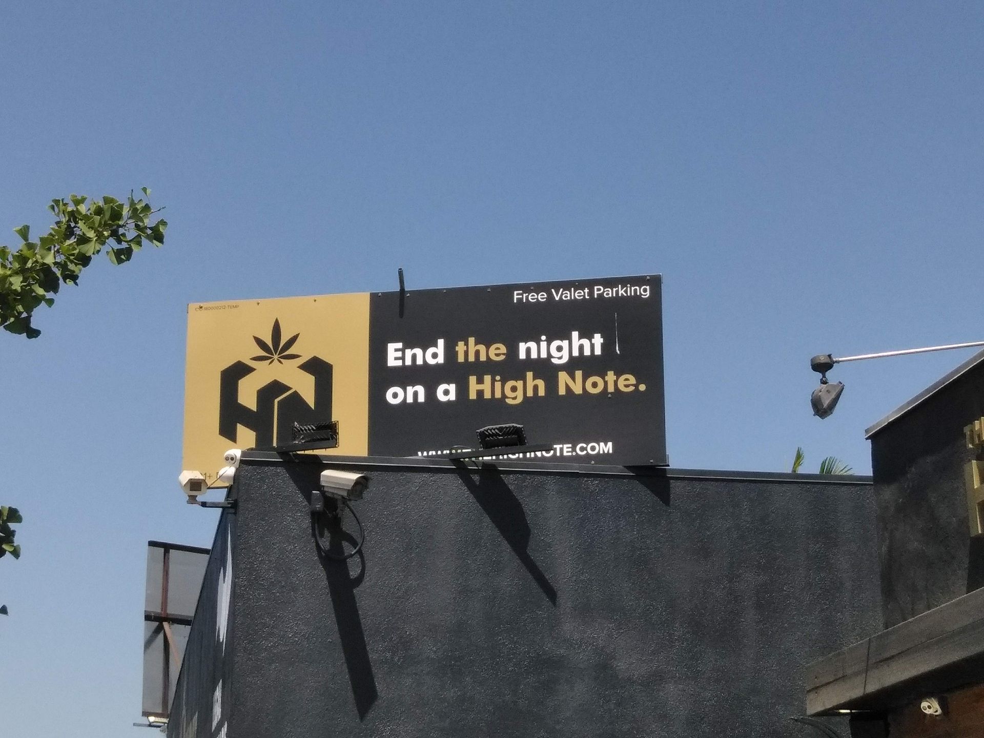Billboard reading “End the night on a High Note” above a dark building against a blue sky