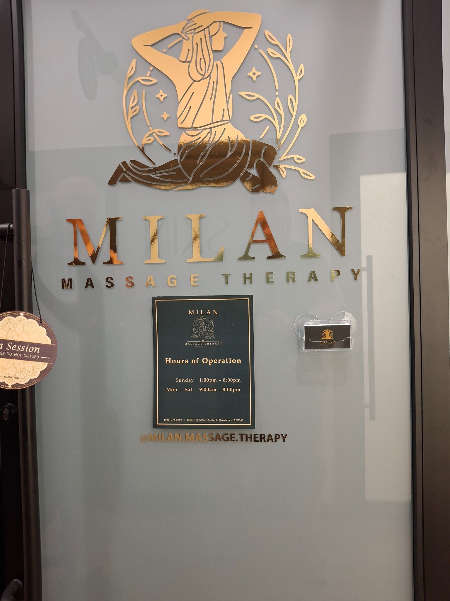 Milan Massage Therapy glass door with gold logo, hours, and contact sign