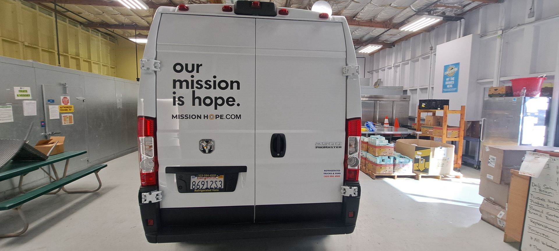 White van in a warehouse loading area with “our mission is hope” printed on the back.