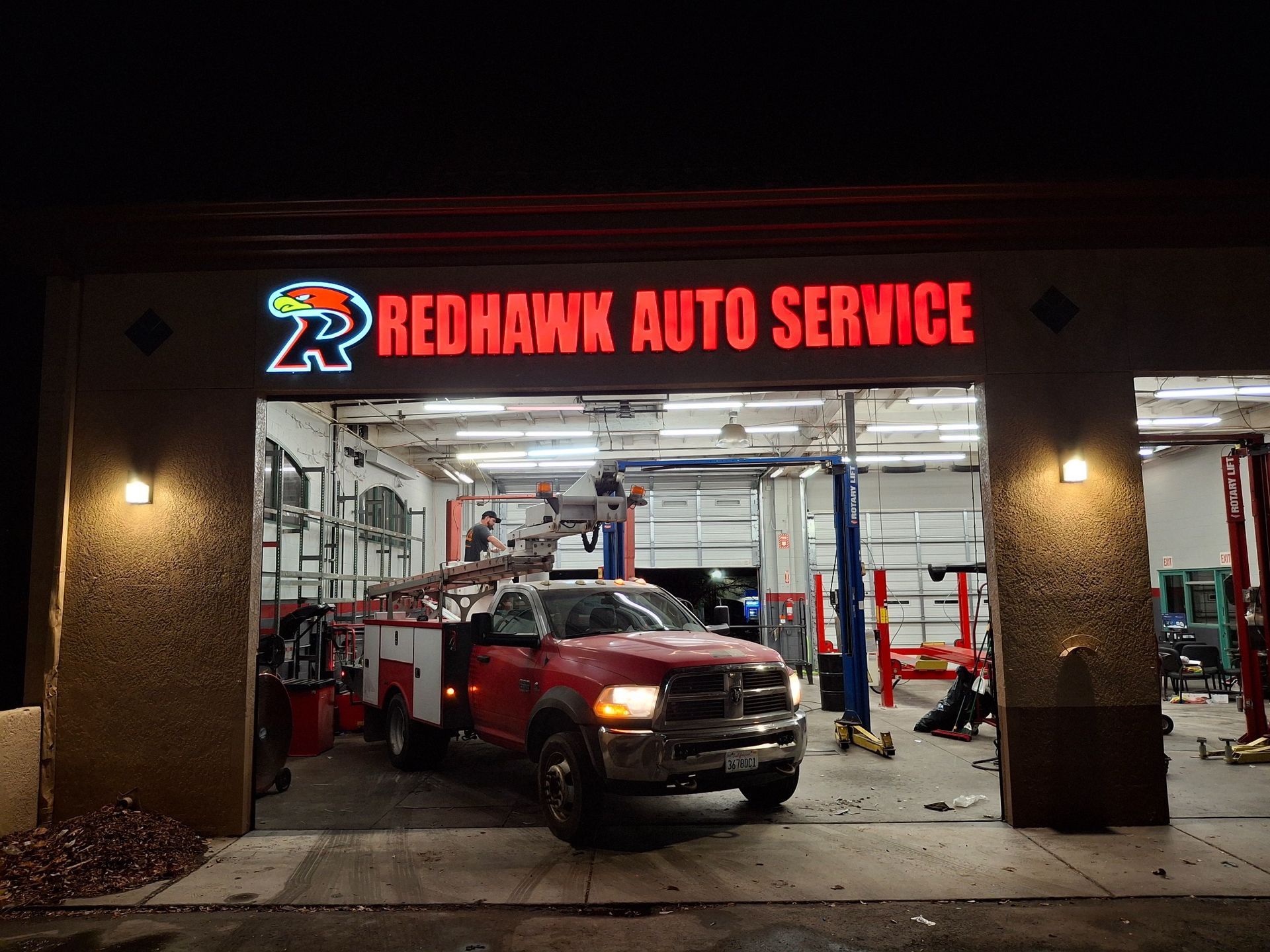 Redhawk Auto Service garage with a red pickup truck inside at night