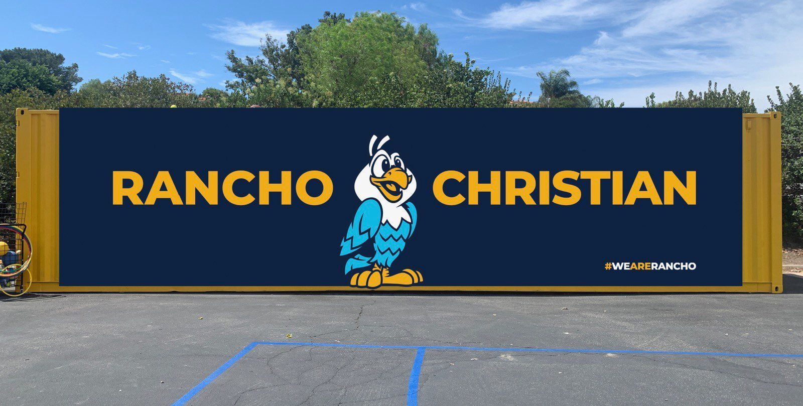 Rancho Christian sign with blue-and-gold eagle mascot on a dark blue wall.