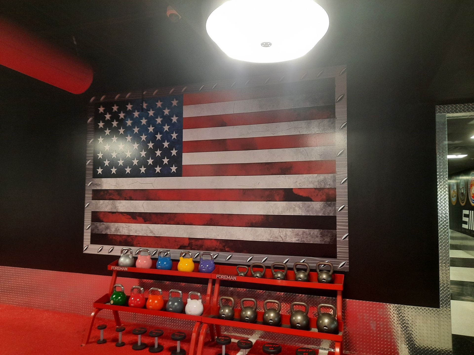 American flag mural above a red shelf of colorful bottles in a dimly lit room