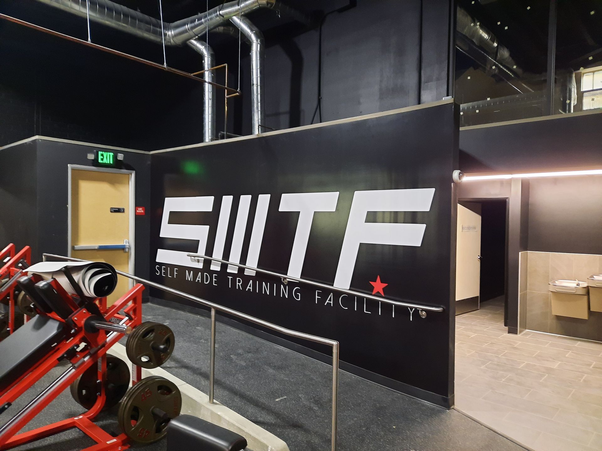 Black banner with large white “SWTF” logo in an industrial gym or facility interior
