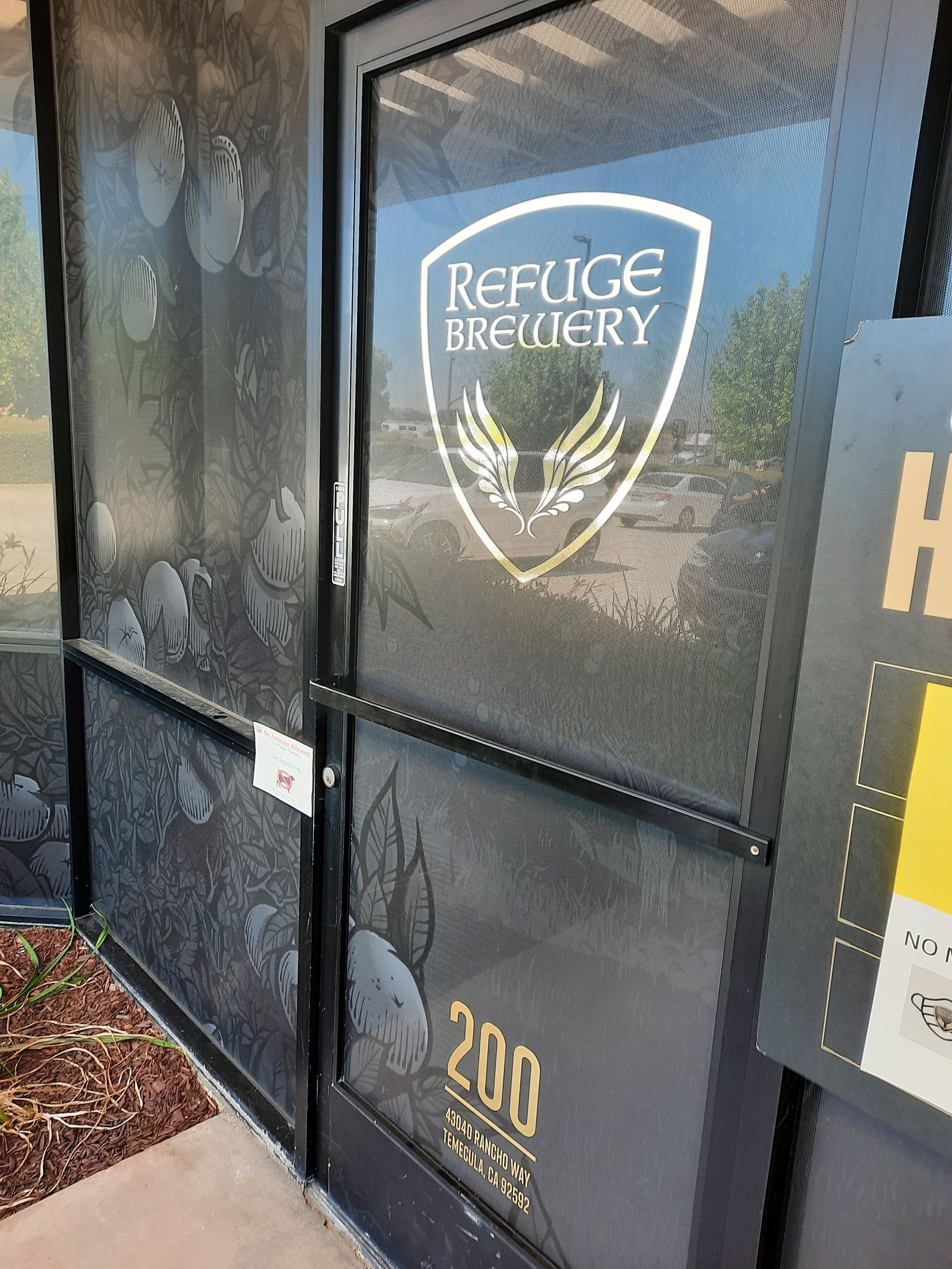 Refuge Brewery logo on a black storefront door with reflective glass panels