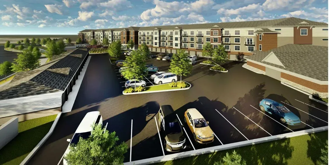 An aerial view of a parking lot with cars parked in front of a building.