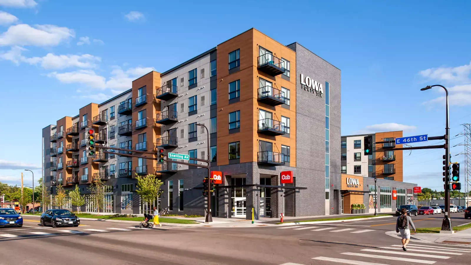 A large apartment building is sitting on the corner of a city street.