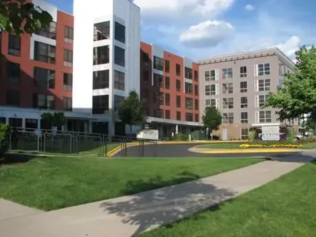 A large building with a lot of windows is surrounded by grass and trees.