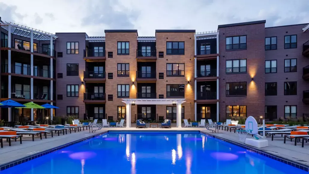 A large apartment building with a large swimming pool in front of it.