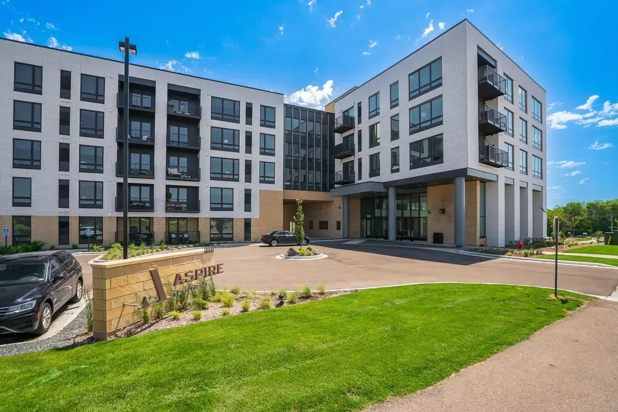A large apartment building with a lot of windows and a car parked in front of it.
