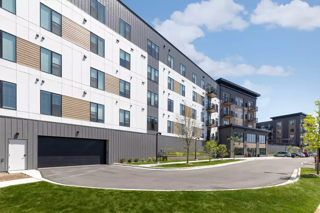 A large apartment building with a parking garage in front of it.