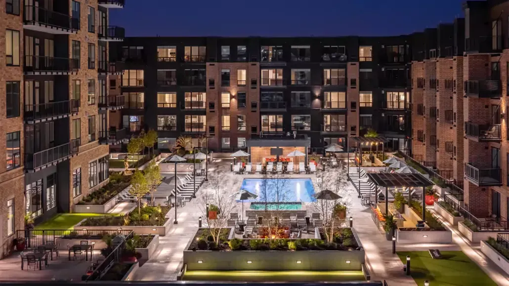 A large apartment building with a swimming pool in the middle of it.