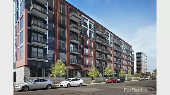 A large apartment building with cars parked in front of it.