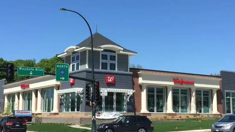 A large building with a lot of windows is sitting on the corner of a street.