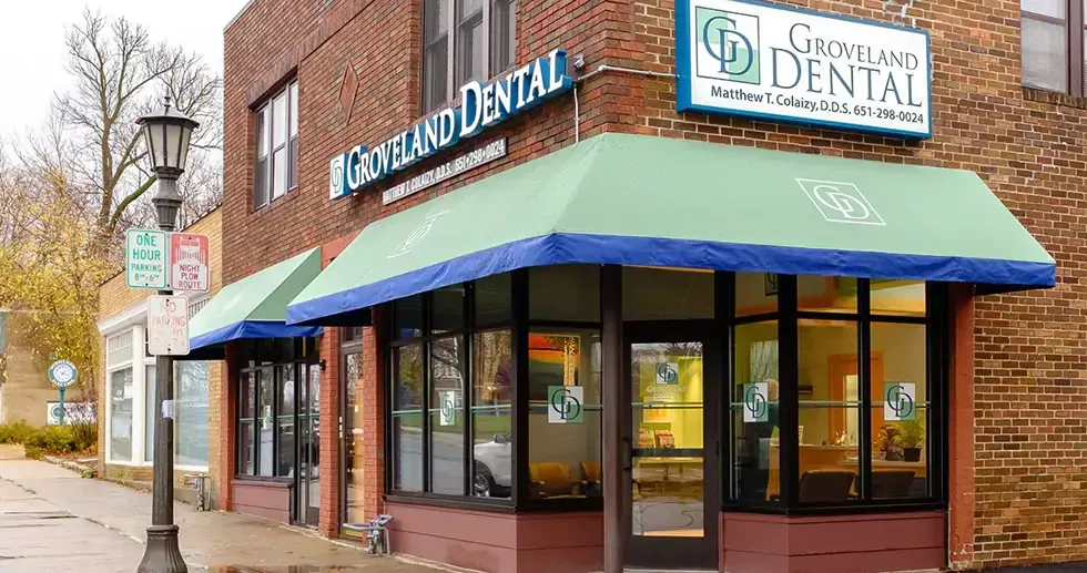 A dental office with a green awning on the side of it.