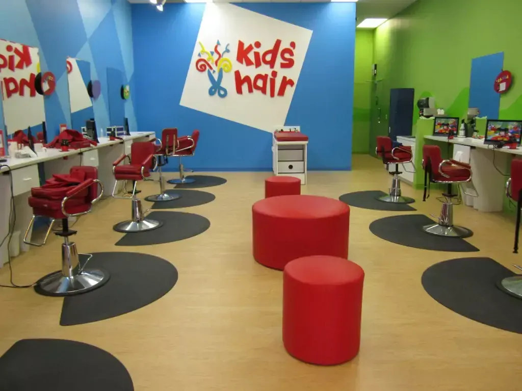 A kids hair salon with red chairs and ottomans