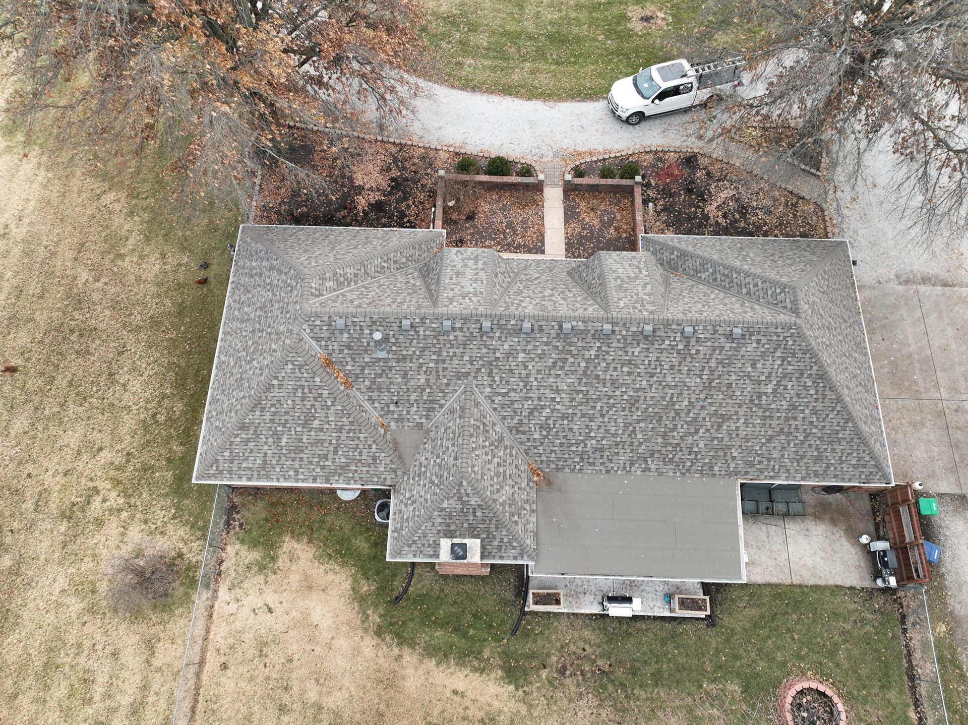 Overhead view of a house with a gray roof, small porch, and a white truck in the driveway.