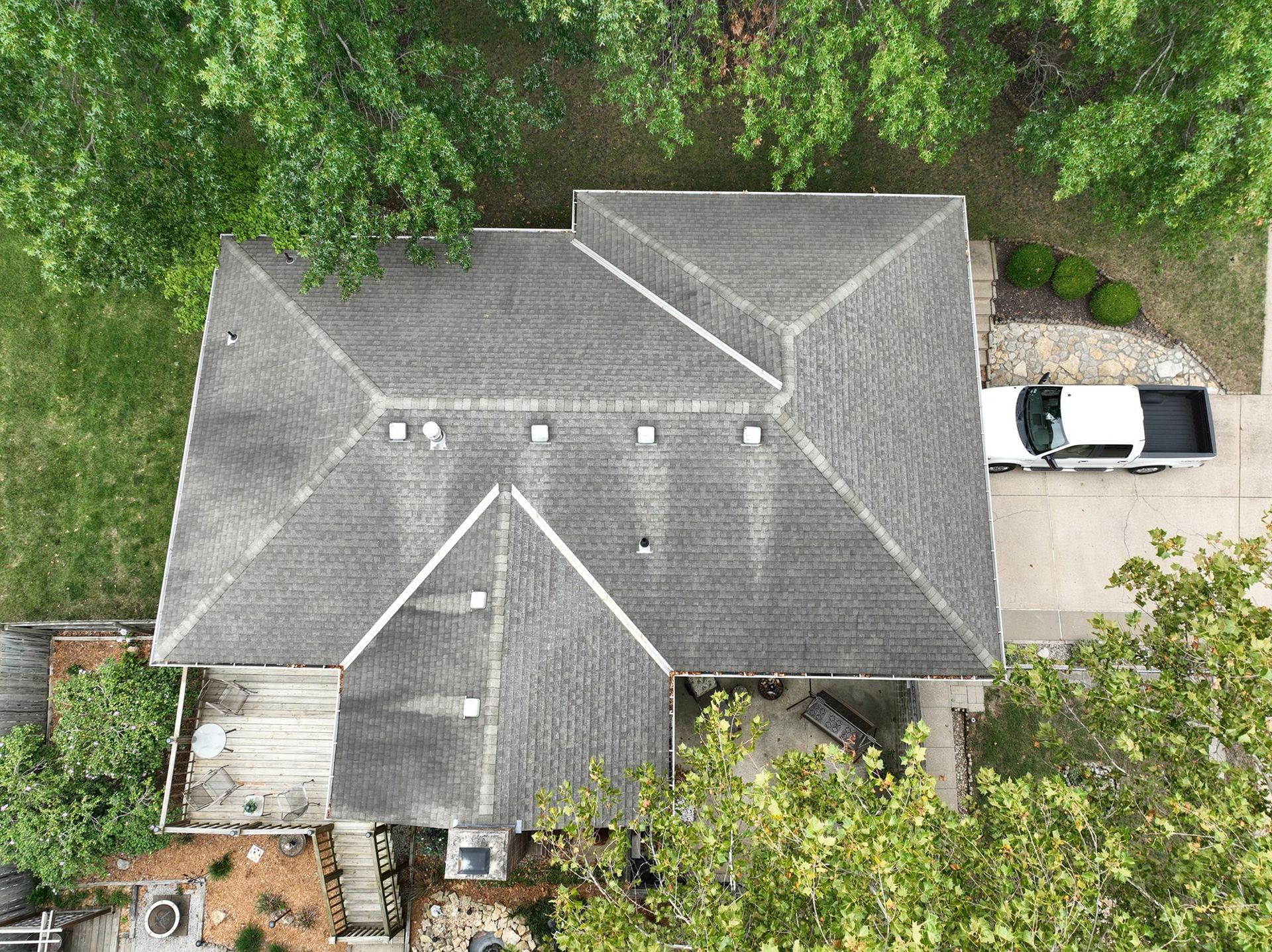 Overhead view of a gray asphalt shingle roof on a house with a white truck parked in the driveway.