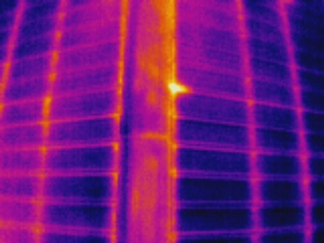 Thermal image of a solar panel. A hot spot (yellow/orange) indicates an electrical fault.