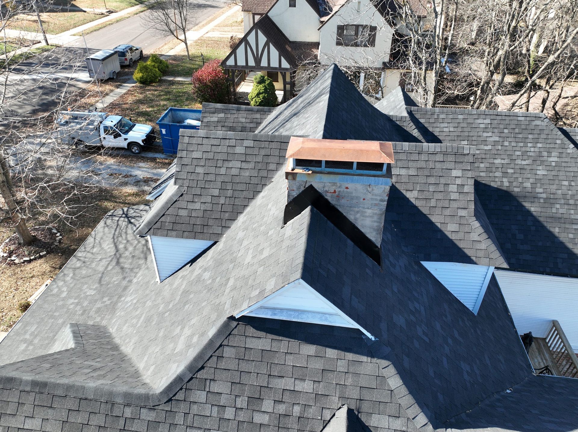 Overhead view of a house roof with a brick chimney and various roof angles.