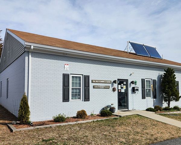 A white brick building with black shutters and a solar panel on the roof.