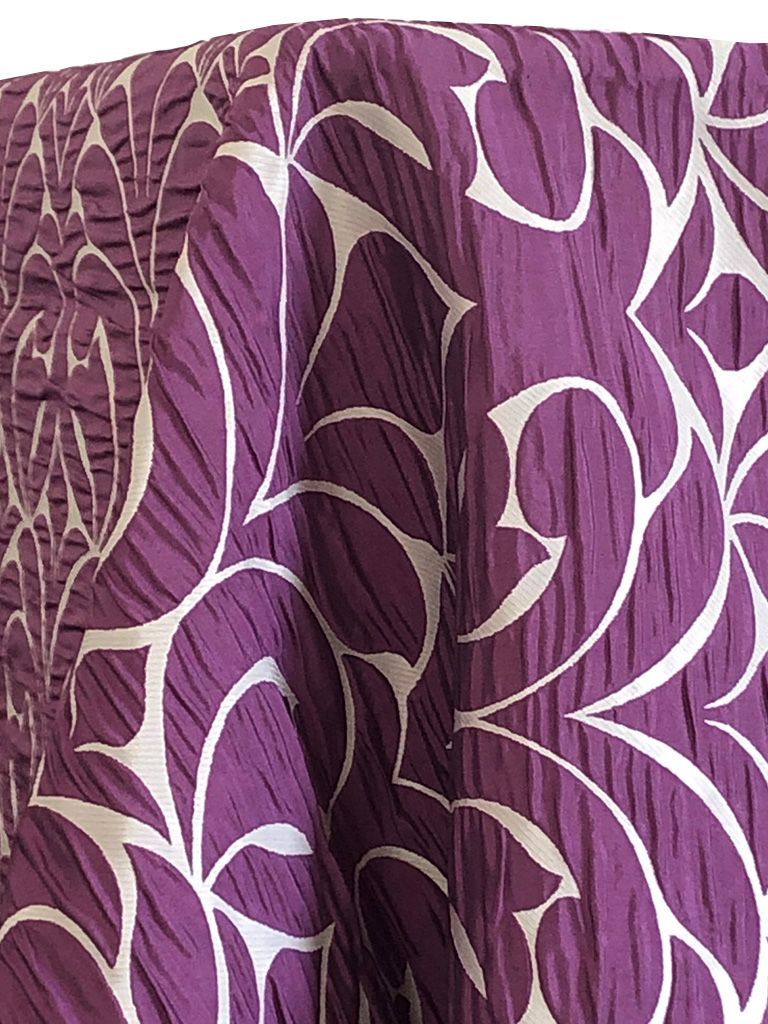 Purple tablecloth with white abstract leaf-like pattern; fabric has a textured, crinkled appearance.