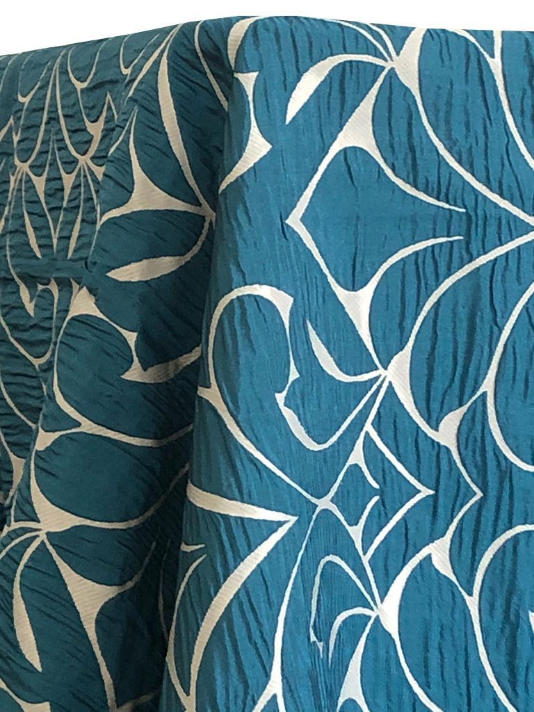 Teal fabric with a white floral pattern, draped.