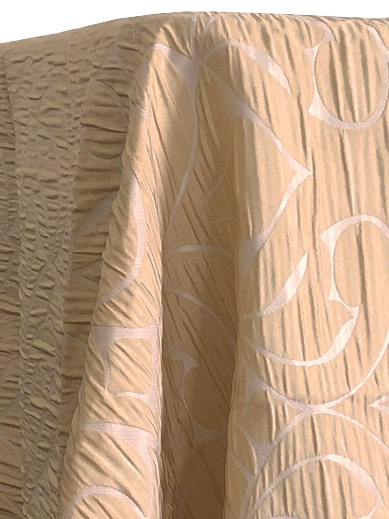 Beige fabric draped, with rippled texture on the left and a pattern of curved lines and shapes on the right.