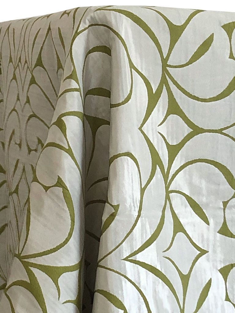 White fabric with an olive green abstract floral pattern draped over a surface.