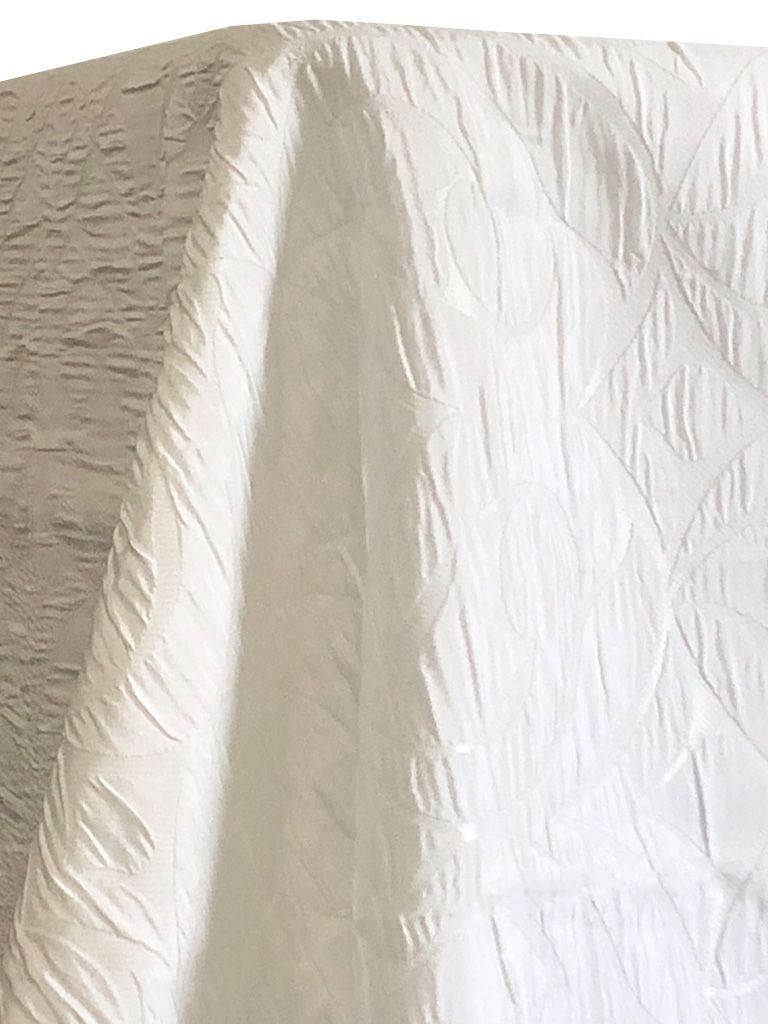 White textured fabric with a quilted pattern, draped.
