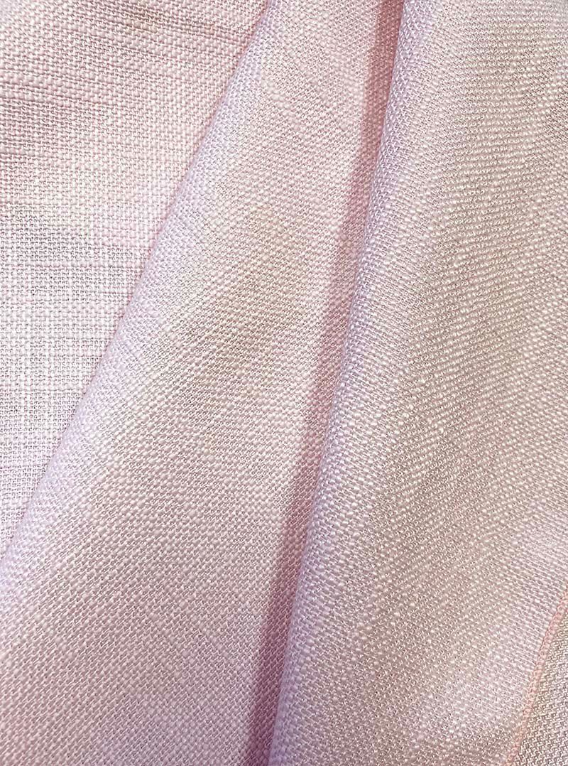 Pink woven fabric, draped and folded with visible texture and subtle color variations.