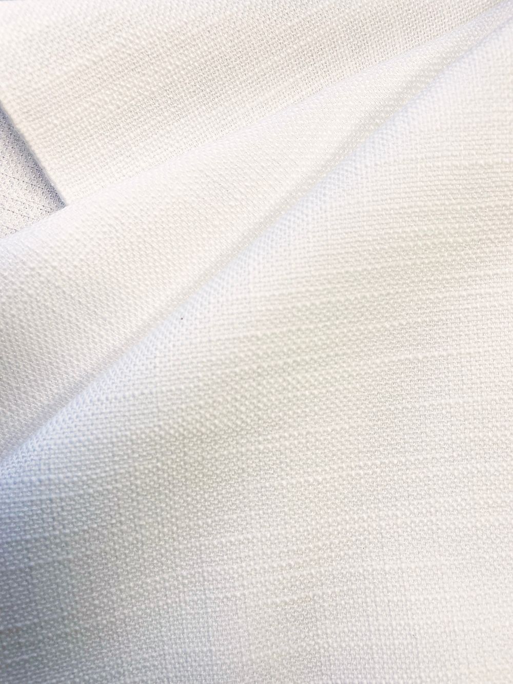 Close-up of white fabric, with a woven texture, draped in folds.