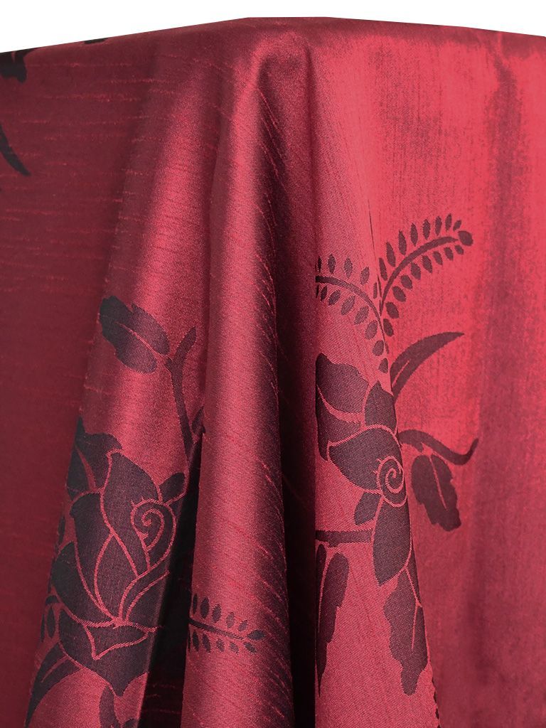 Crimson fabric with dark floral pattern draped over a surface.