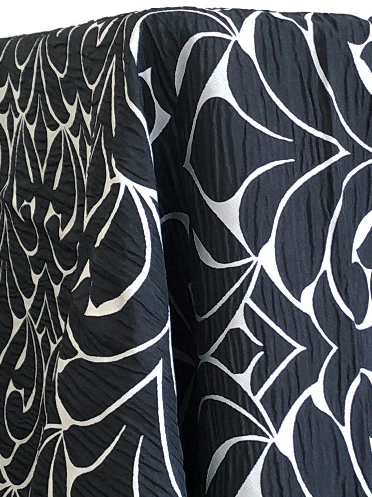 Black fabric with a white floral pattern, draped.