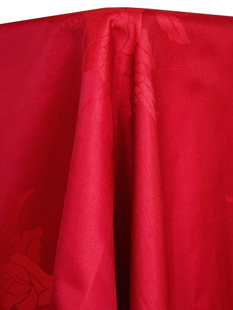 Close-up of a red fabric tablecloth with folds and a subtle floral pattern.