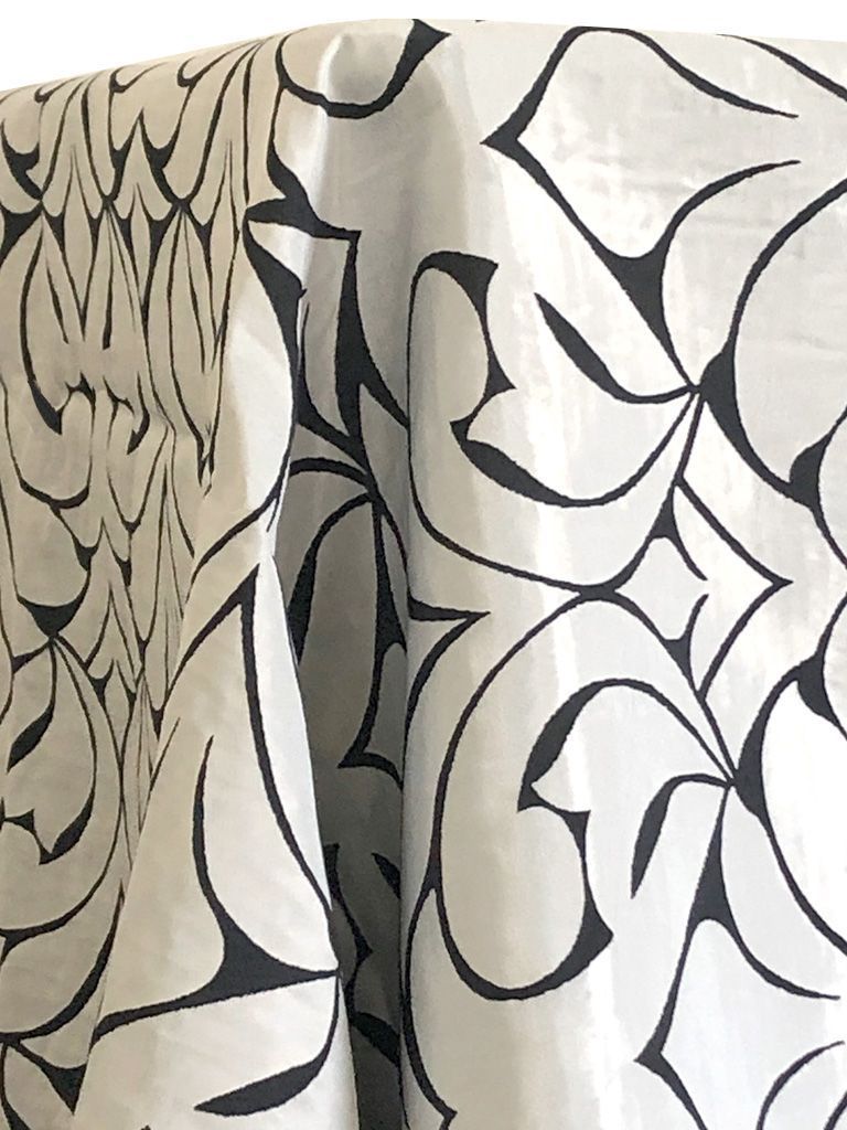 White fabric with black, swirling floral pattern.