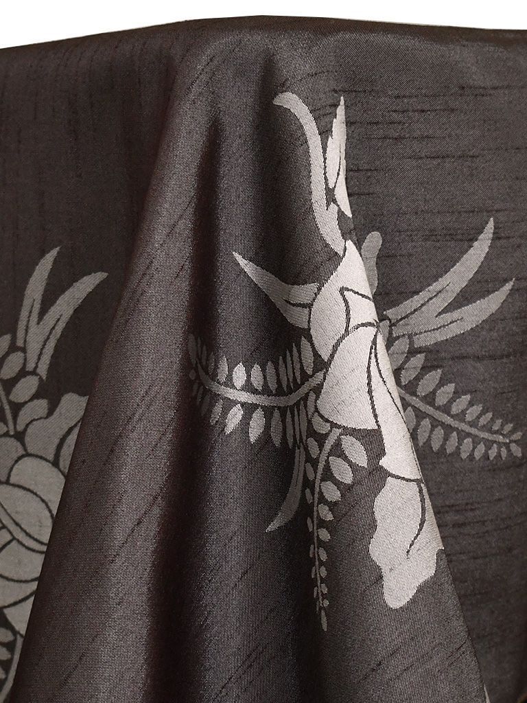Black tablecloth with gray floral design, draped, textured.