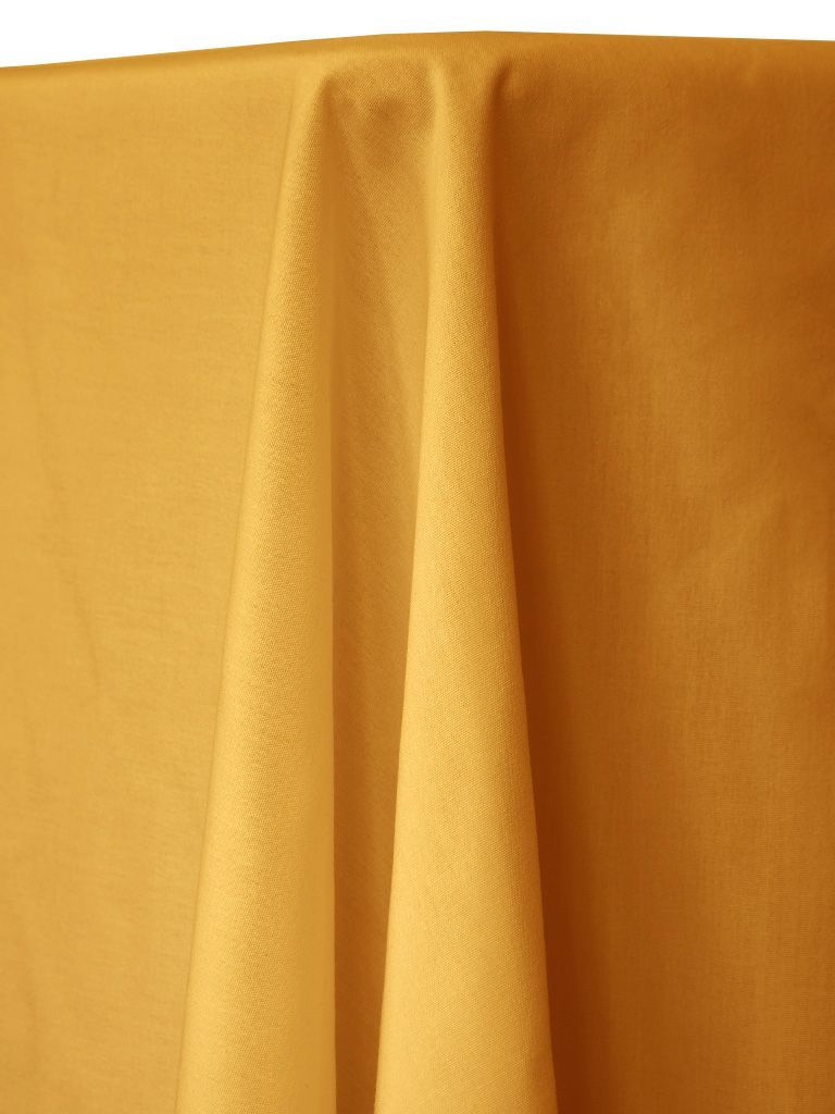 Yellow fabric draped over a table, with folds and texture visible.