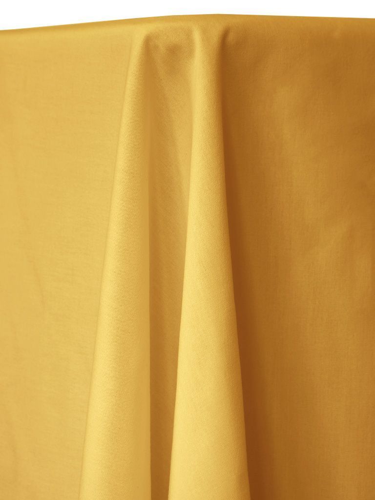 Yellow draped tablecloth, lit from above, covering a table.