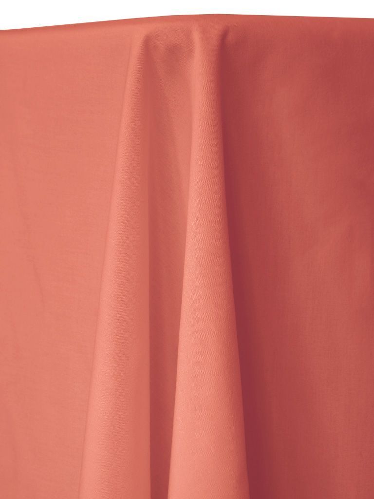 Coral-colored tablecloth draped on a table. The fabric has a subtle, textured pattern with folds.
