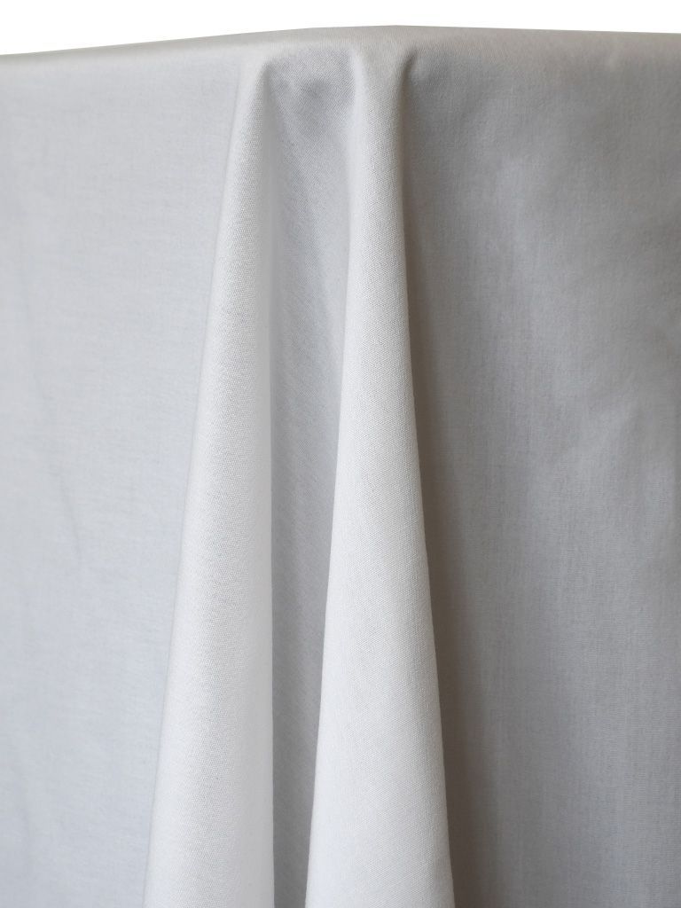 White tablecloth draped over a table, with folds and texture visible.