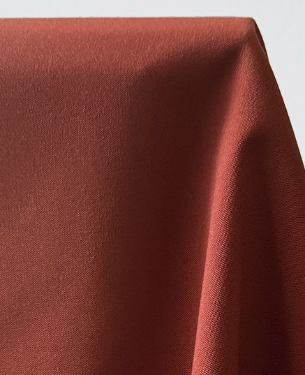 Close-up of rust-colored fabric draped in soft folds.