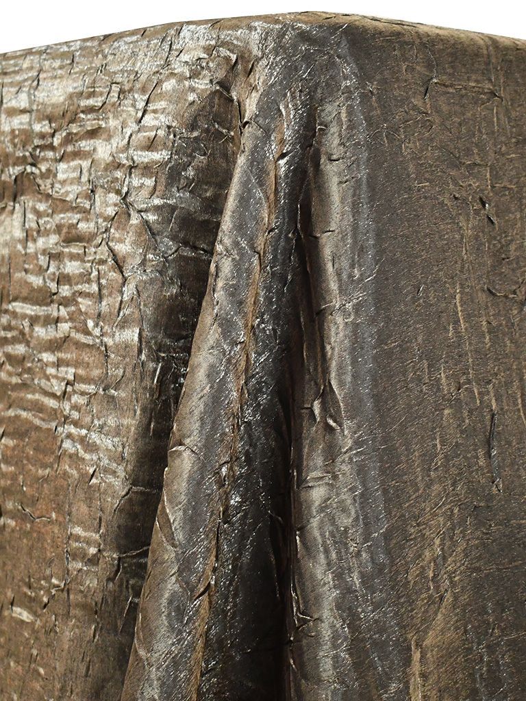 Close-up of a weathered, dark brown, textured surface with angular folds and cracks.