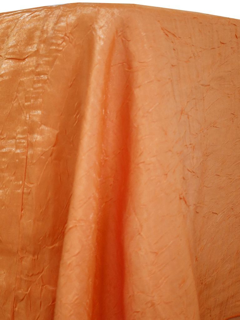 Peach-colored fabric draped, with folds and texture.