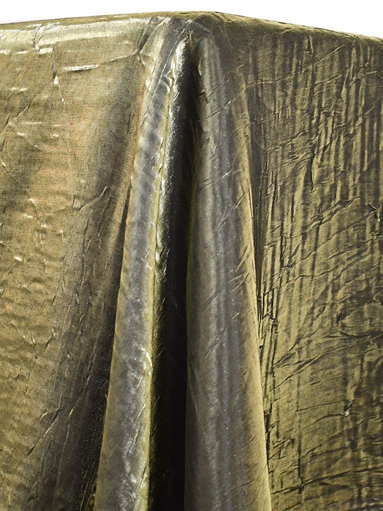 Gold and dark fabric draped over a surface, with folds and a sheen.